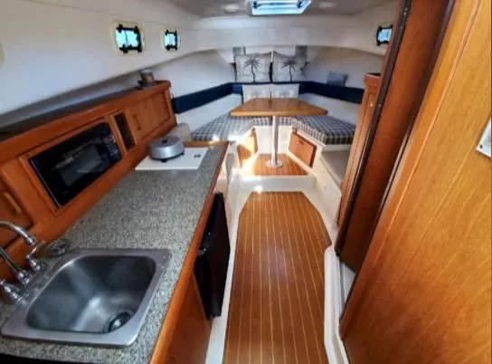 Slide: The Image of 1999 Mainship Pilot 30 interior with kitchenette, sink, and cozy seating area. - 7