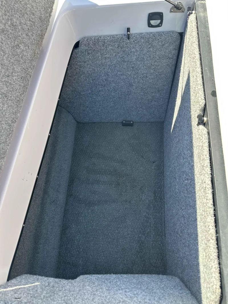 Slide: The Image of Storage compartment of a 2007 Sanger V215 boat, featuring gray carpeted interior. - 11