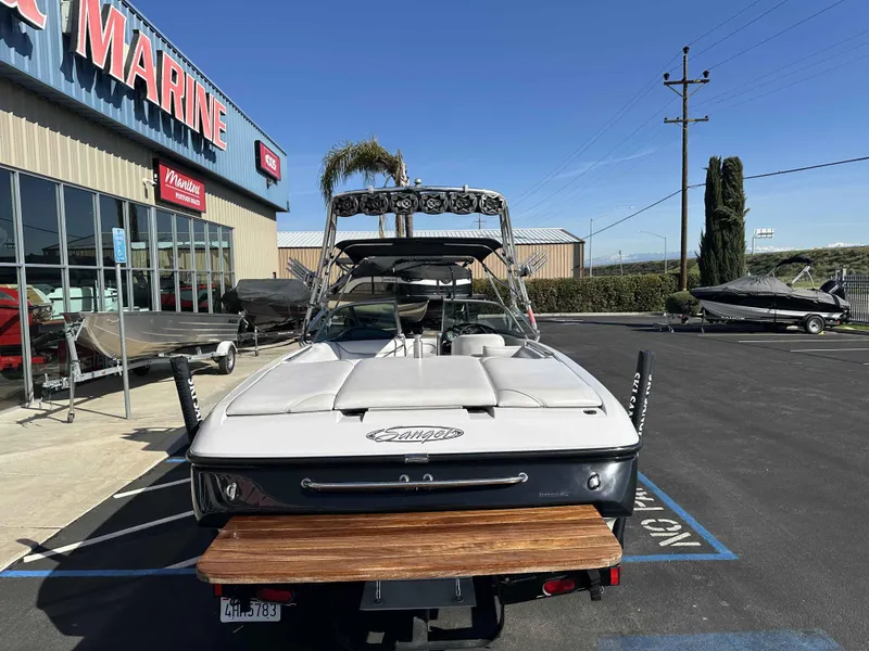 Slide: The Image of 2007 Sanger V215 boat parked outside a marine dealership on a sunny day. - 3