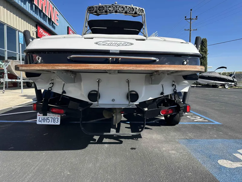 Slide: The Image of Rear view of a 2007 Sanger V215 boat parked outside a marine shop. - 4