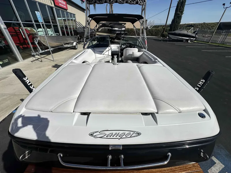 Slide: The Image of 2007 Sanger V215 boat with white seating, parked outdoors near a dealership. - 5