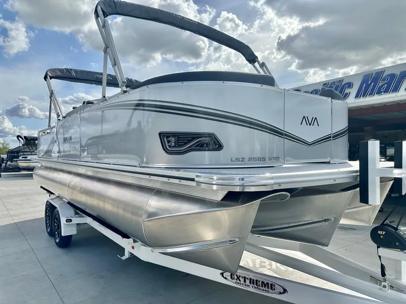 Slide: The Image of 2025 Avalon 25' LSZ Platinum Versatile Rear Bench pontoon boat on trailer, under cloudy sky. - 9