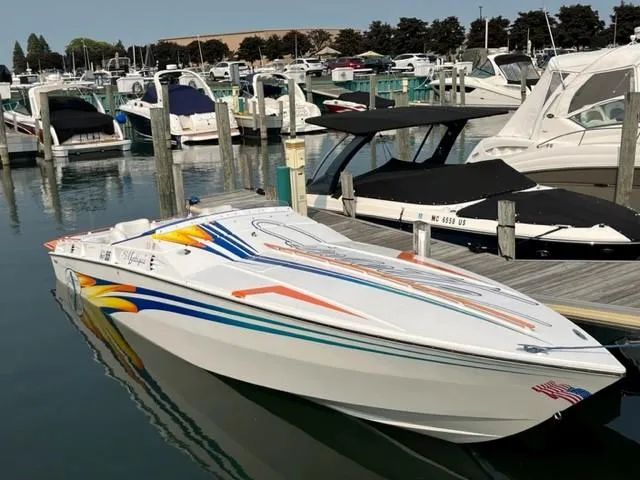 Slide: The Image of 2001 Cigarette Mystique speedboat docked at a marina, featuring vibrant graphics. - 0