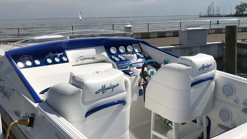 Slide: The Image of 2001 Cigarette Mystique boat interior with white seating and control panel by the water. - 2