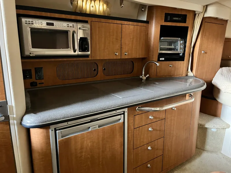 Slide: The Image of 2006 Sea Ray 340 Sundancer yacht kitchen with wood cabinets, microwave, and sink. - 16