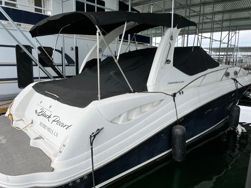 Slide: The Image of 2006 Sea Ray 340 Sundancer boat docked, covered with black canopy and tarp. - 4