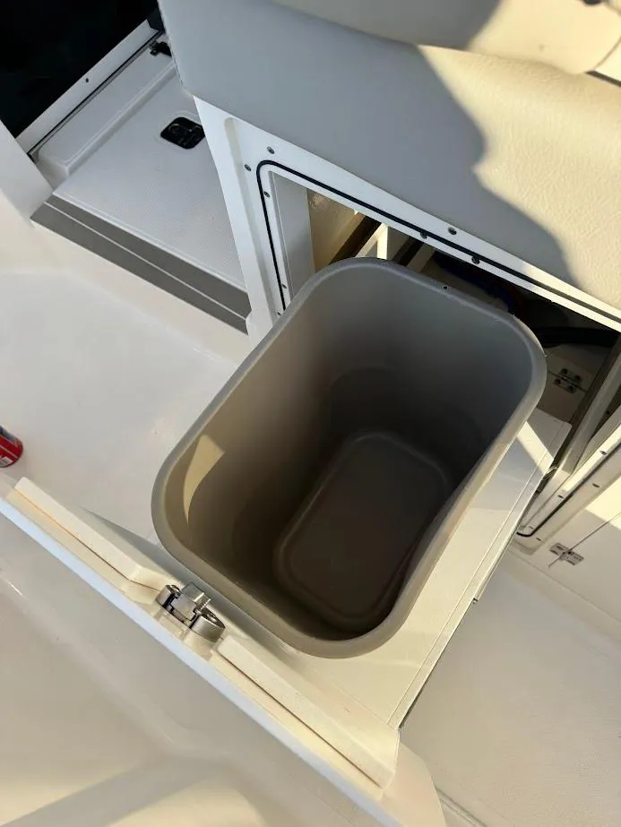 Slide: The Image of 2024 Pursuit S 358 Sport boat interior with built-in trash bin compartment. - 48