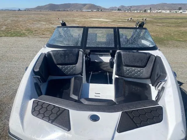 Slide: The Image of 2022 Scarab 195 ID boat with black seating, parked on a gravel area with mountains in the background. - 12