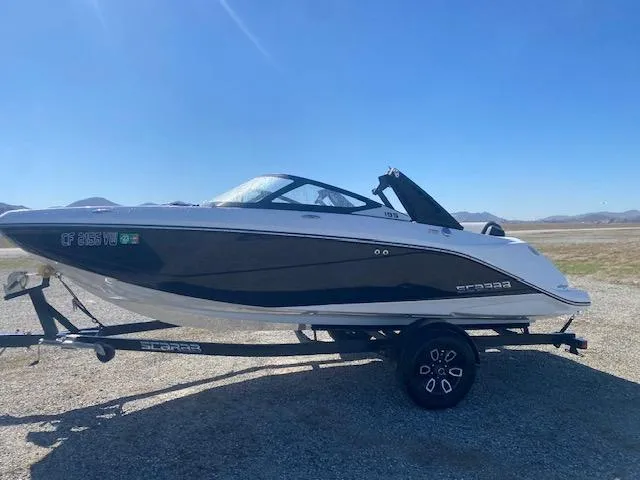 Slide: The Image of 2022 Scarab 195 ID boat on trailer, parked outdoors under clear blue sky. - 3