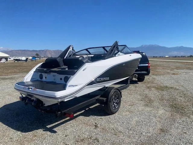 Slide: The Image of 2022 Scarab 195 ID boat on trailer, parked outdoors with mountains in background. - 7