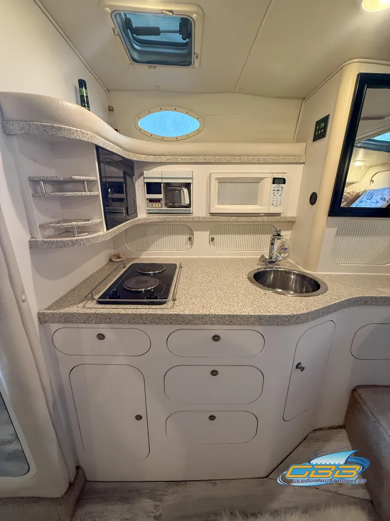 Slide: The Image of Interior of 2000 Rinker 340 Fiesta Vee boat kitchen with stove, sink, and microwave. - 33