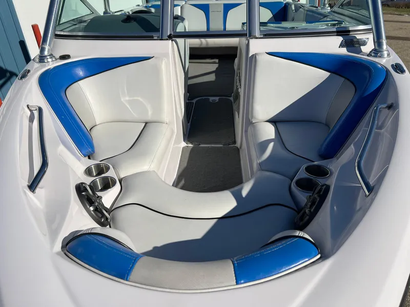 Slide: The Image of 2008 Nautique 210 boat interior with blue and white seating and cup holders. - 12