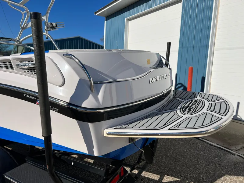 Slide: The Image of 2008 Nautique 210 boat with swim platform, parked near blue building. - 14