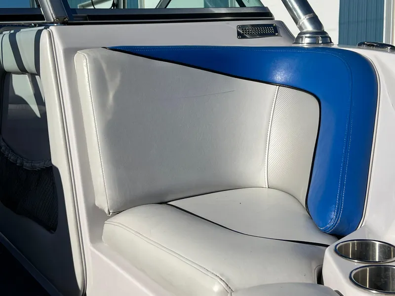 Slide: The Image of 2008 Nautique 210 boat interior with white and blue seating, featuring cup holders. - 5