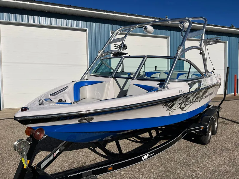 Slide: The Image of 2008 Nautique 210 boat with blue accents on a trailer, parked near a blue building. - 9