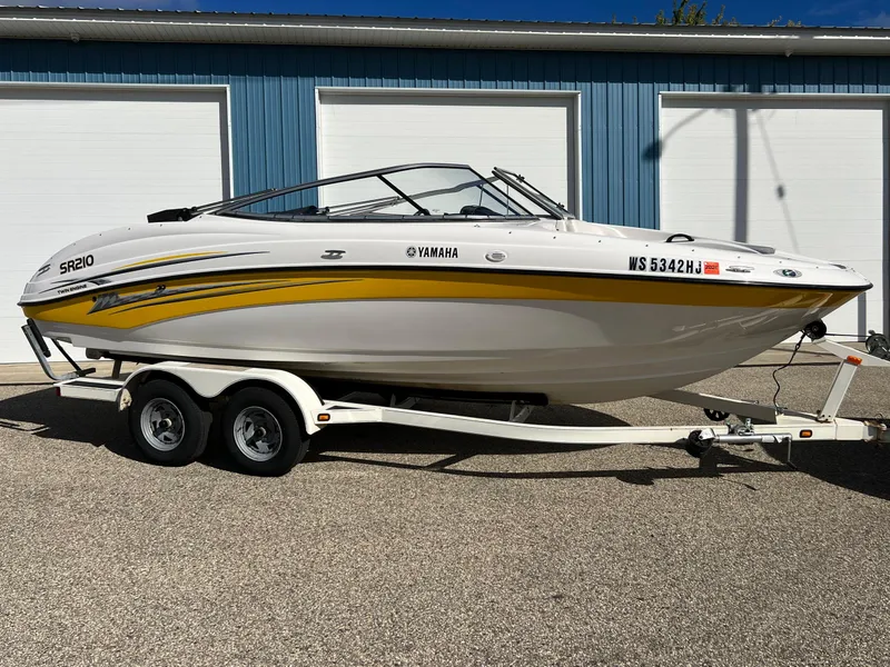 Slide: The Image of 2006 Yamaha Boats SR 210 on trailer, white with yellow accents, parked outside blue garage. - 8