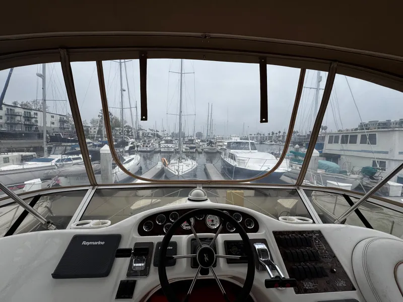 Slide: The Image of 1998 Sea Ray 370 Aft Cabin yacht helm with marina view, featuring steering wheel and controls. - 23