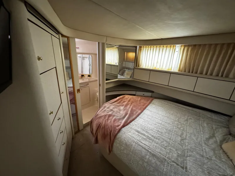 Slide: The Image of 1998 Sea Ray 370 Aft Cabin bedroom with cozy bed, storage, and ensuite bathroom. - 45
