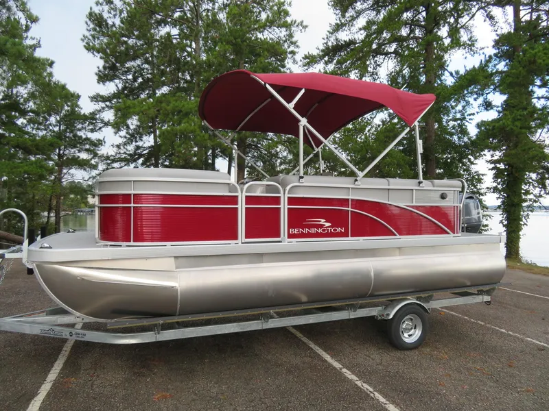Slide: The Image of 2021 Bennington 20SLV pontoon boat with red canopy on a trailer, surrounded by trees. - 3