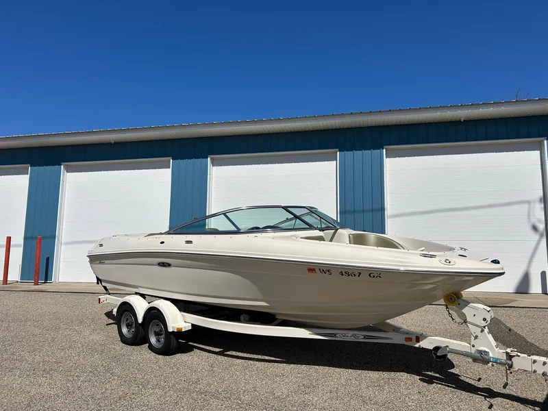 Slide: The Image of 2005 Sea Ray 200SP boat on trailer, parked outside blue storage facility. - 0