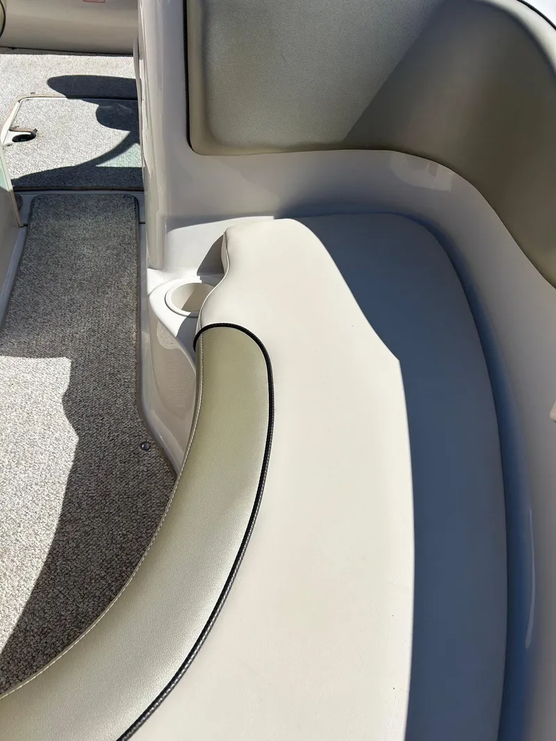 Slide: The Image of Interior seating of a 2005 Sea Ray 200SP boat, featuring beige upholstery and cup holder. - 34