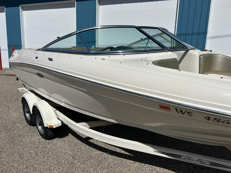 Slide: The Image of 2005 Sea Ray 200SP boat on trailer, parked outdoors near blue and white building. - 9