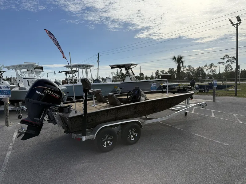 Slide: The Image of 2025 Xpress Hyper-Lift Bass Series boat on trailer in parking lot under cloudy sky. - 2