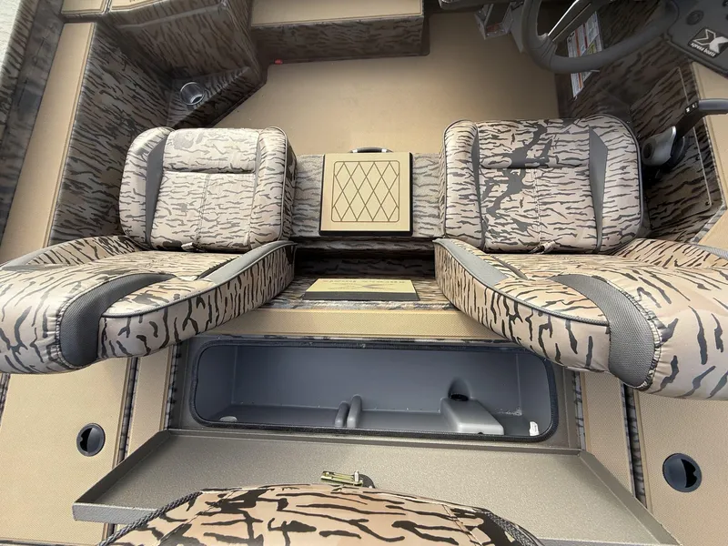 Slide: The Image of 2025 Xpress Hyper-Lift Bass Series boat interior with camo seats and storage compartment. - 7
