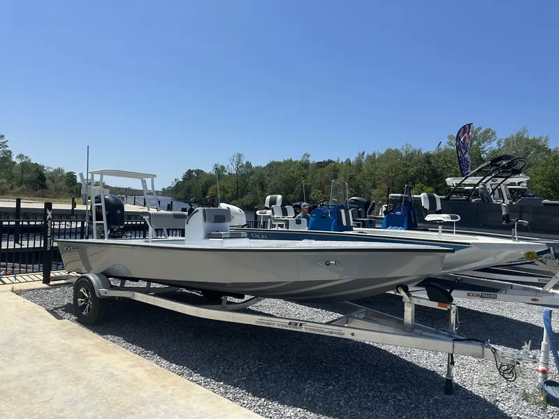 Slide: The Image of 2025 Xpress Skiff 185 boat on trailer, displayed outdoors under clear blue sky. - 1