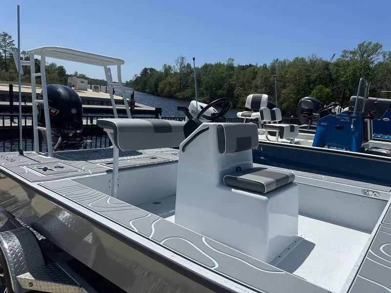 Slide: The Image of 2025 Xpress Skiff 185 boat docked by a river, featuring a sleek design and modern seating. - 4