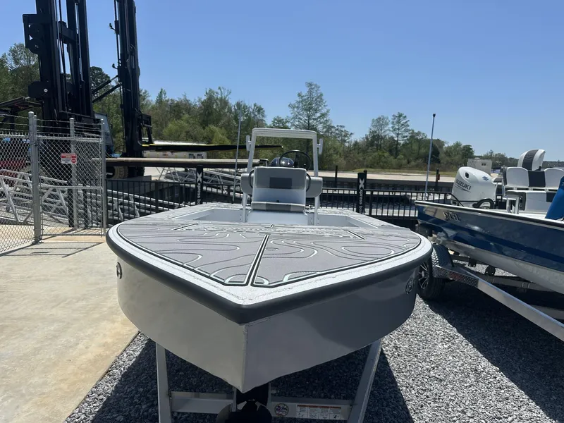 Slide: The Image of 2025 Xpress Skiff 185 boat displayed outdoors on gravel, with clear blue sky. - 6