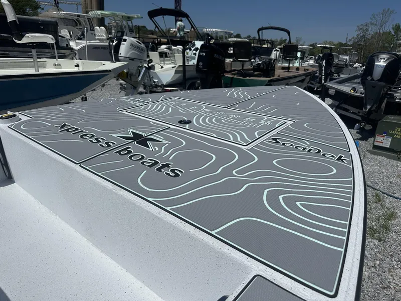 Slide: The Image of 2025 Xpress Skiff 185 boat with SeaDek flooring, displayed outdoors among other boats. - 8