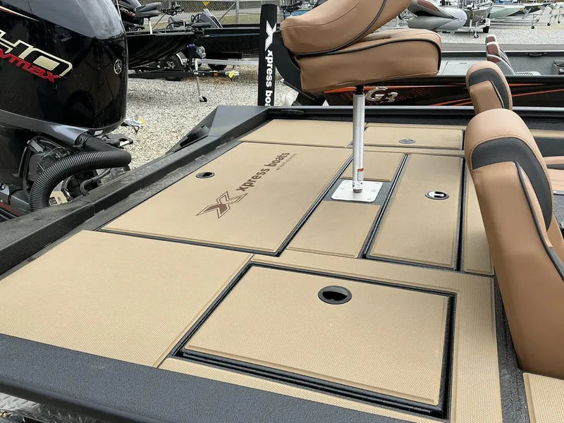 Slide: The Image of 2025 Xpress Hyper-Lift Bass Series boat deck with tan seating and storage compartments. - 4