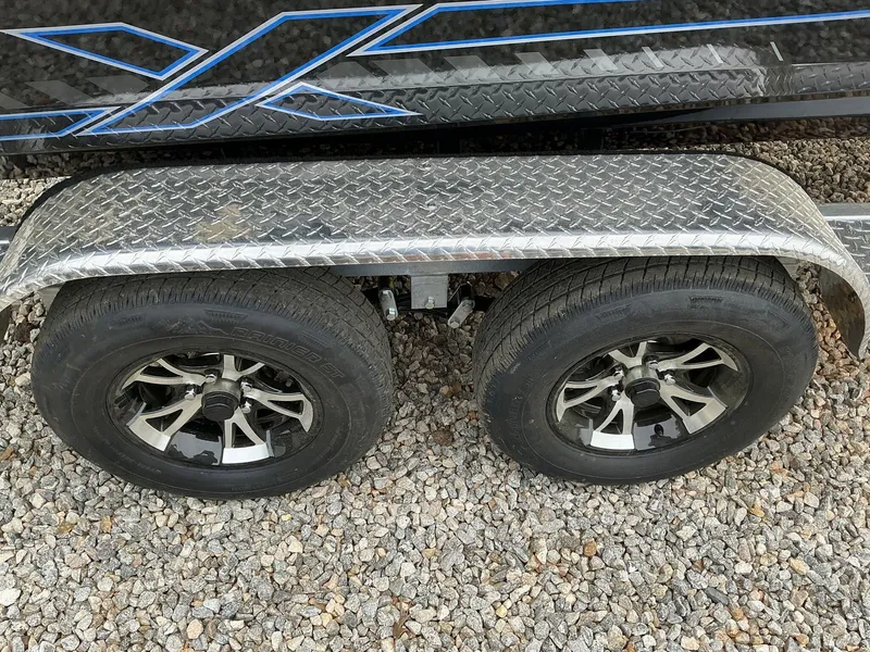 Slide: The Image of 2025 Xpress Hyper-Lift Crappie Series H20 trailer wheels on gravel surface. - 11
