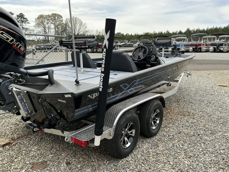 Slide: The Image of 2025 Xpress Hyper-Lift Crappie Series H20 boat on a trailer, parked on gravel. - 12