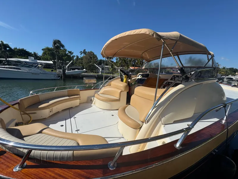 Slide: The Image of 2005 Apreamare Don Giovanni boat with tan seating and canopy, docked in a sunny marina. - 2