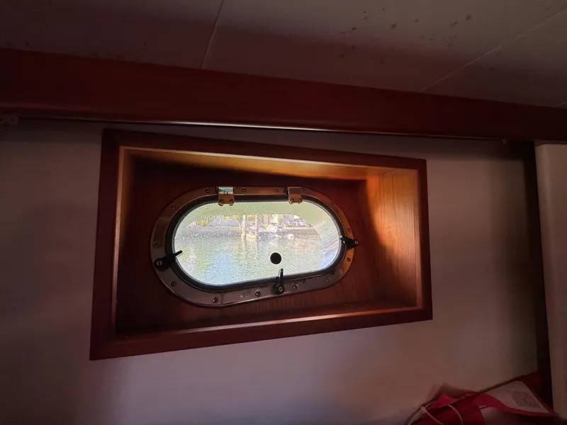Slide: The Image of Porthole window inside 2005 Apreamare Don Giovanni boat, showcasing wooden frame and exterior view. - 26