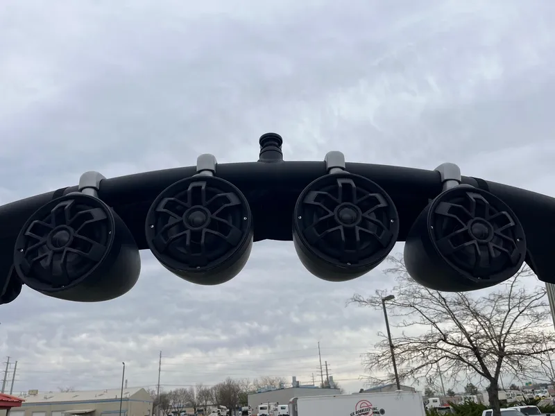 Slide: The Image of Four black speakers mounted on a bar, under a cloudy sky. - 37