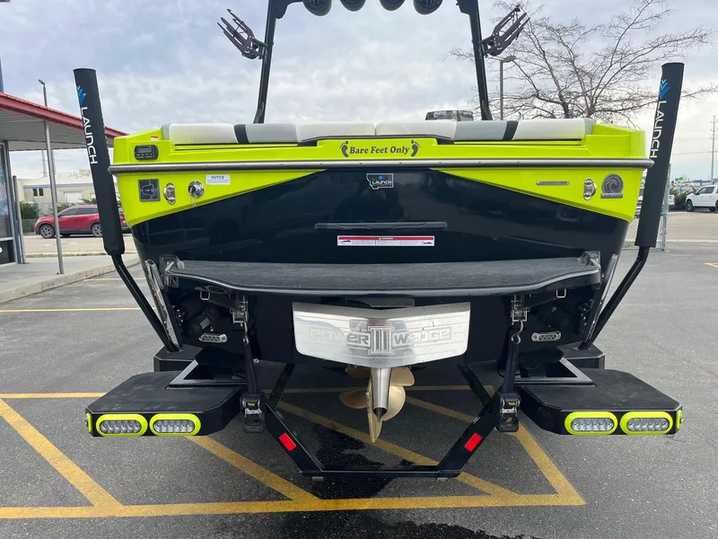 Slide: The Image of 2023 Axis T220 boat rear view with vibrant green accents and "Bare Feet Only" decal. - 5