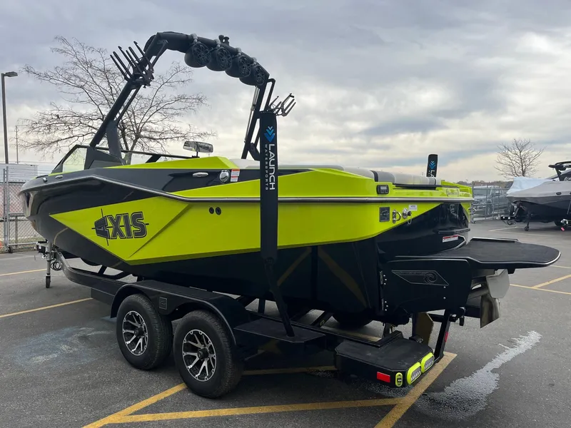 Slide: The Image of 2023 Axis T220 boat in vibrant green and black, parked on a trailer in a lot. - 8