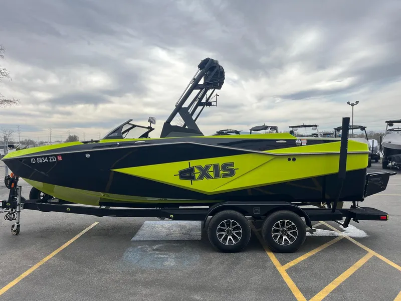 Slide: The Image of 2023 Axis T220 boat in vibrant green and black on a trailer, parked outdoors. - 9