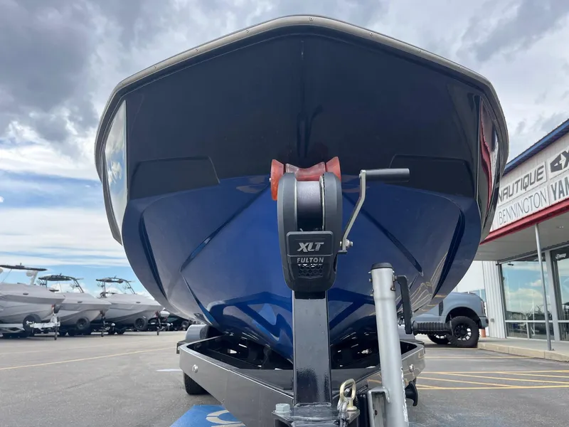 Slide: The Image of 2023 Axis T220 boat on trailer, parked at dealership under cloudy sky. - 11