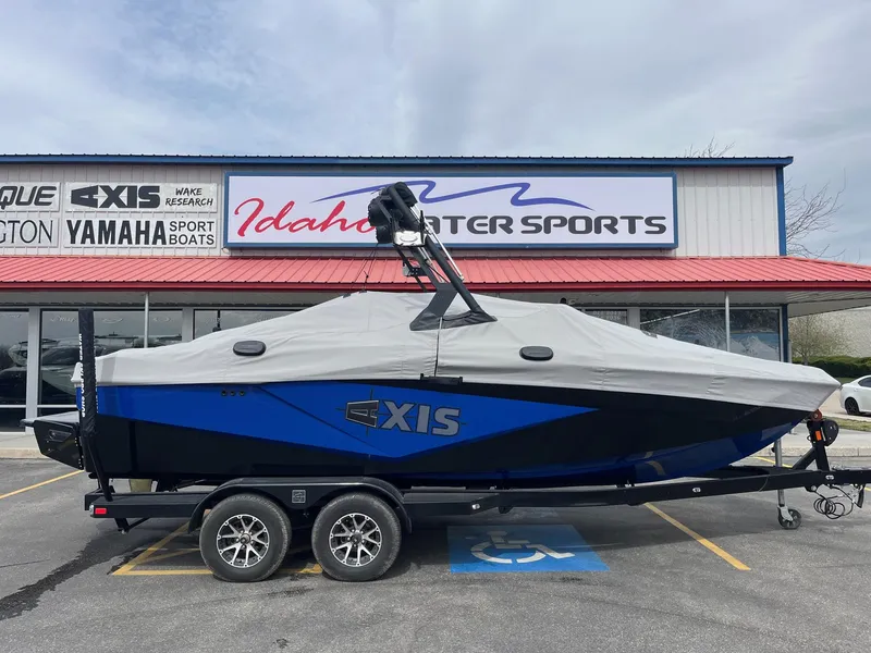 Slide: The Image of 2023 Axis T220 boat covered, parked at Idaho Water Sports dealership. - 2