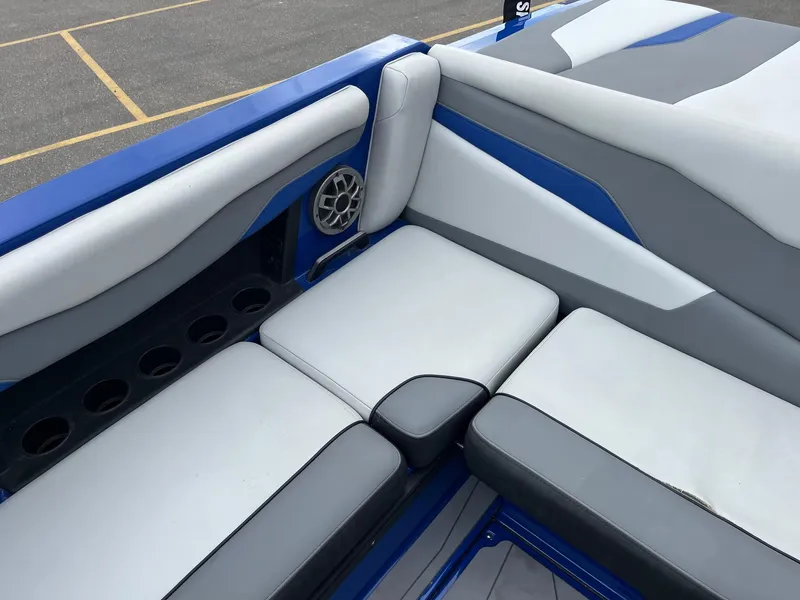 Slide: The Image of 2023 Axis T220 boat interior with gray and blue seating, cup holders, and speaker. - 21