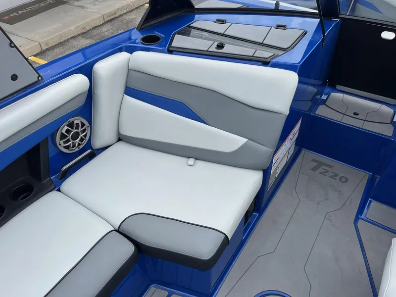 Slide: The Image of 2023 Axis T220 boat interior with blue and gray seating, speaker, and cup holders. - 25
