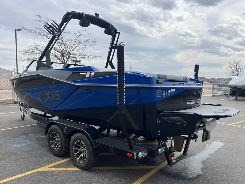 Slide: The Image of 2023 Axis T220 boat on trailer, blue and black design, parked outdoors. - 8