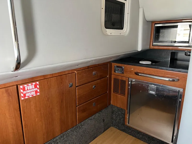 Slide: The Image of 2015 Formula 350 Crossover Bowrider interior with kitchenette, wood cabinets, and stainless steel appliances. - 26
