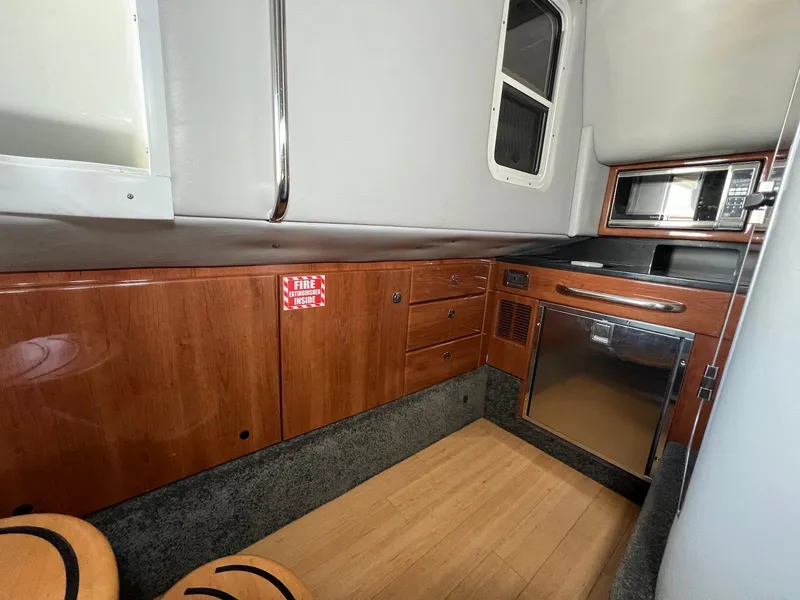Slide: The Image of 2015 Formula 350 Crossover Bowrider interior with wood cabinetry and compact kitchen area. - 27