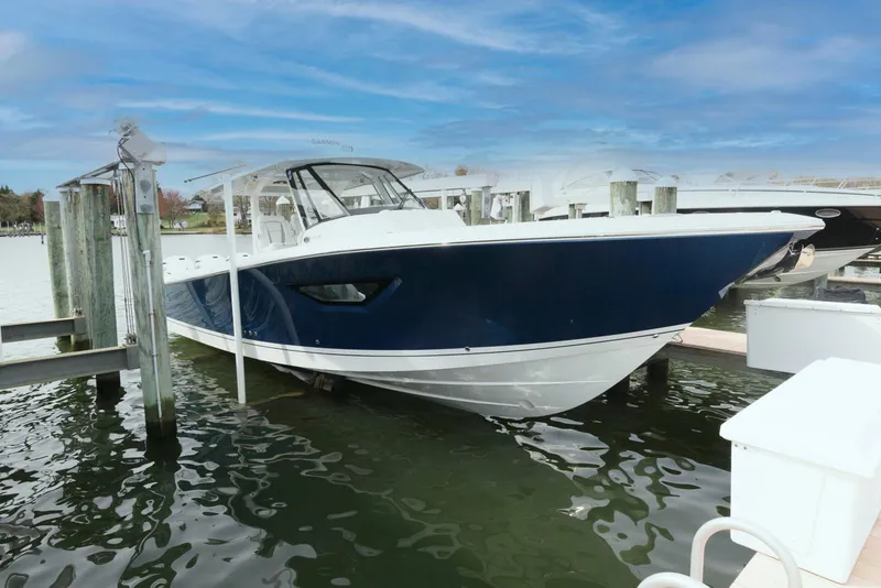 The Image of 2022 Pursuit S 378 Sport boat docked in marina, featuring sleek blue and white design. - 0