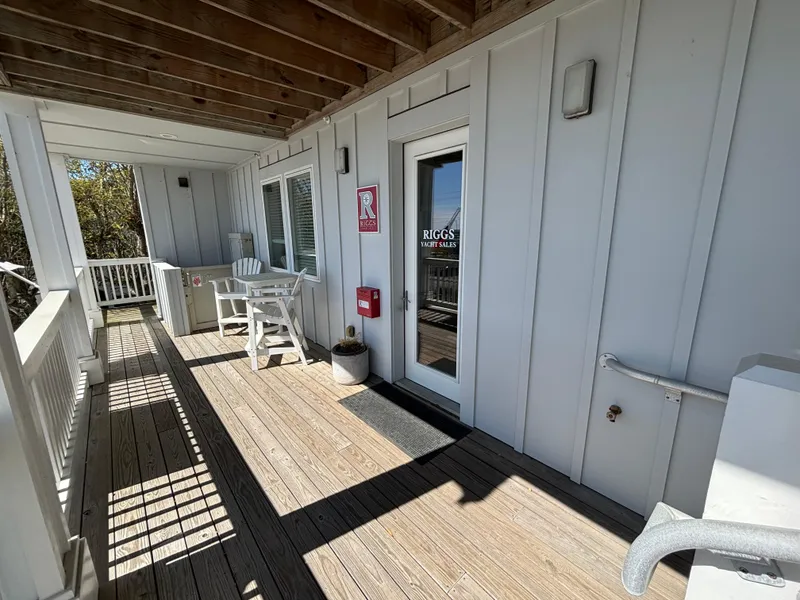 Slide: The Image of Wooden deck with white chairs outside Riggs Yacht Sales office. - 23